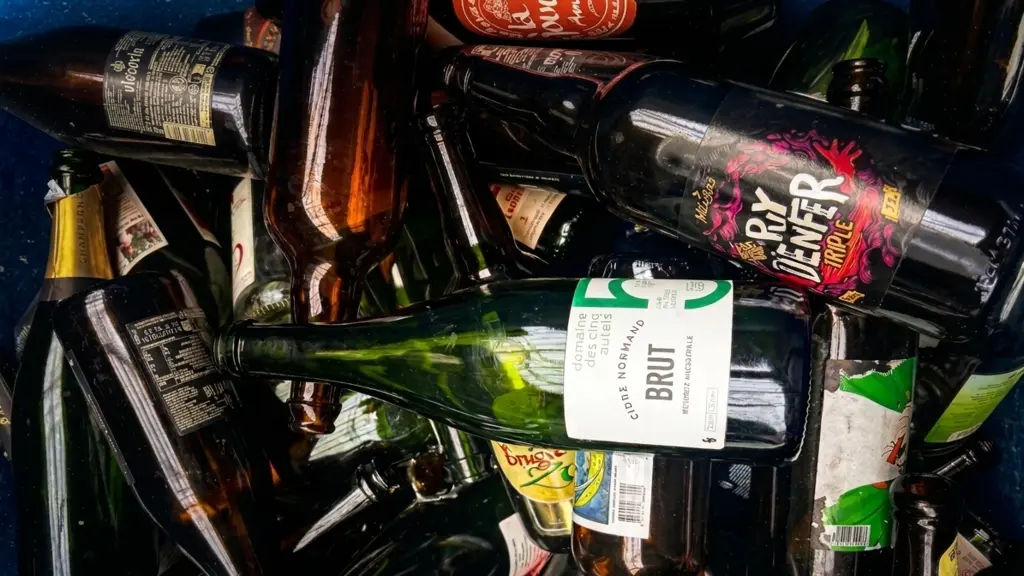 Contenedor de recogida lleno de botellas de vidrio vacías, incluida una botella de sidra seca del Domaine des Cinq Autels